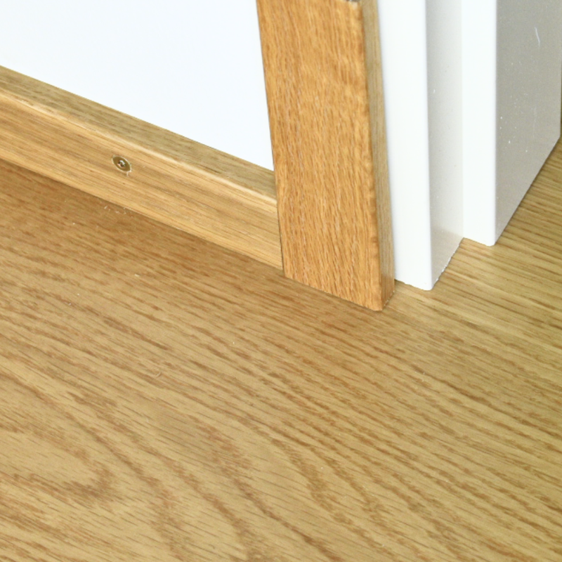 Tammi peitelista 12 x 42 mm lakattu asennettuna valkoisen karmin viereen